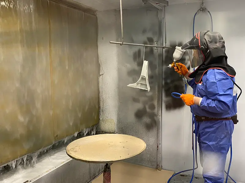 Man protective suit wet paint spraying product with water curtain in background